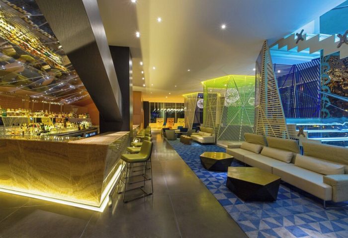 W Mexico City gay-friendly hotel bar and lounge area. Stylish design with colorful geometric patterns, comfortable seating, and a mirrored bar.