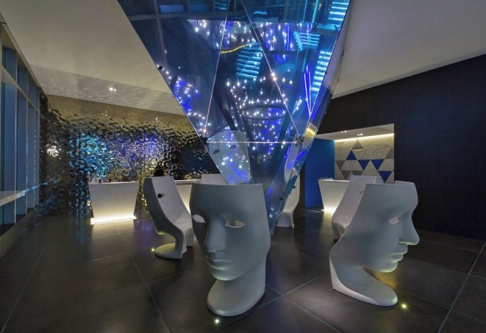 Lobby at W Mexico City, a gay-friendly hotel. Features face-shaped chairs, a mirrored pyramid, and modern design. Gay travel in Mexico City.