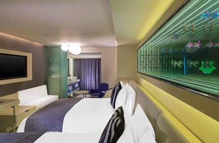 W Mexico City gay-friendly hotel room. Modern design with king bed, infinity mirror art, TV, sofa, and partial view of the bathroom.