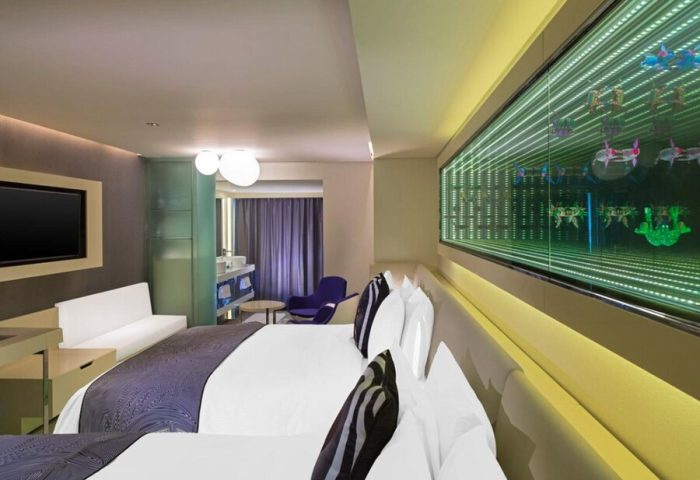 W Mexico City gay-friendly hotel room. Modern design with king bed, infinity mirror art, TV, sofa, and partial view of the bathroom.