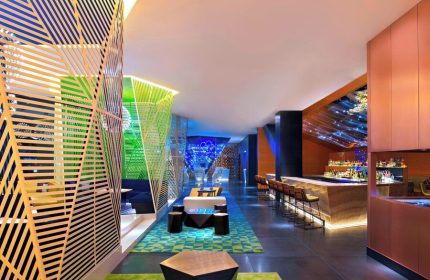W Mexico City gay-friendly hotel bar. Stylish interior with colorful geometric designs, lounge area, and bar seating. Modern, vibrant space.