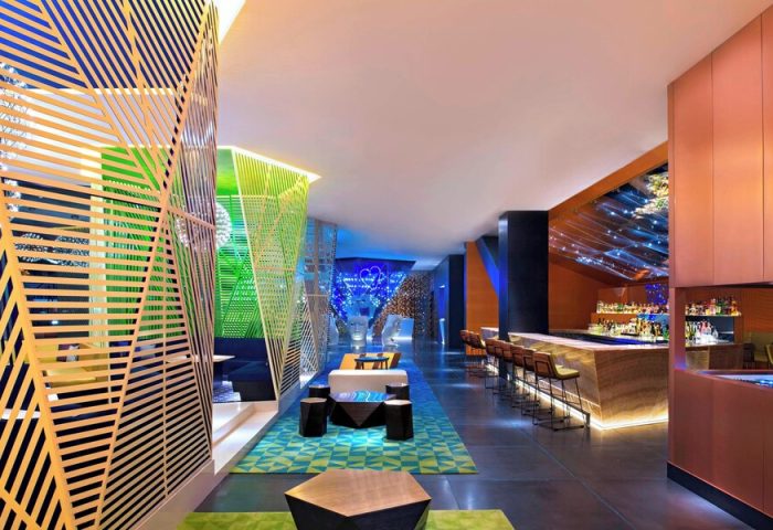 W Mexico City gay-friendly hotel bar. Stylish interior with colorful geometric designs, lounge area, and bar seating. Modern, vibrant space.