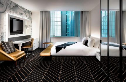 W Montréal gay-friendly hotel room. Modern design with bed, desk, chair, and geometric carpet. Great for gay men's travel in Montreal.