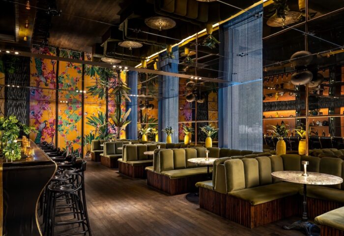 W Montréal gay-friendly hotel lounge. Stylish bar with green velvet booths, floral wallpaper, and mirrored ceiling. Upscale, modern design.