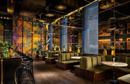 W Montréal gay-friendly hotel lounge. Stylish bar with green velvet booths, floral wallpaper, and mirrored ceiling. Upscale, modern design.