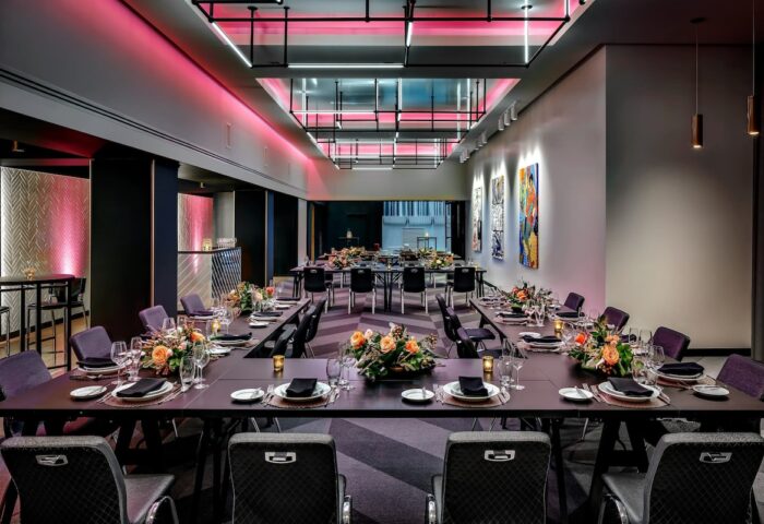 W Montréal gay-friendly hotel event space. Long tables are set with flowers, glasses, and plates. Pink lighting adds a vibrant touch.