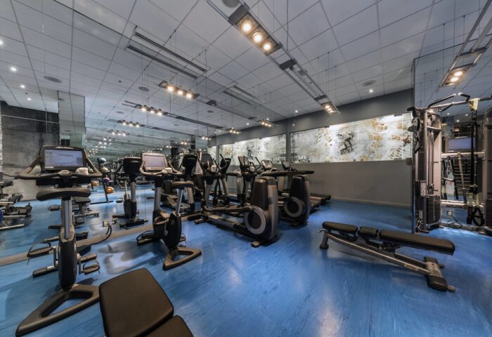 W Montréal gay-friendly hotel gym. Fitness center with treadmills, exercise bikes, weights, and blue flooring. Modern design.