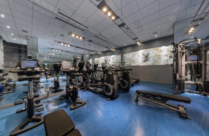 W Montréal gay-friendly hotel gym. Fitness center with treadmills, exercise bikes, weights, and blue flooring. Modern design.