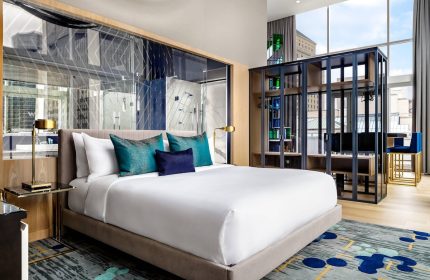 W Montréal gay-friendly hotel room. Modern design with a bed, pillows, closet, and city view. Ideal for gay travelers seeking style.