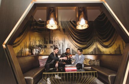 Gay-Friendly Hotel W New York Times Square: Three men toasting drinks in a stylish lounge with gold accents and modern design.