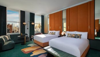 W New York - Union Square hotel room with two beds, city view, sofa, and colorful rug. A gay-friendly hotel for your travel plans.