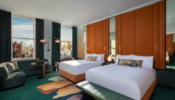 W New York - Union Square hotel room with two beds, city view, sofa, and colorful rug. A gay-friendly hotel for your travel plans.