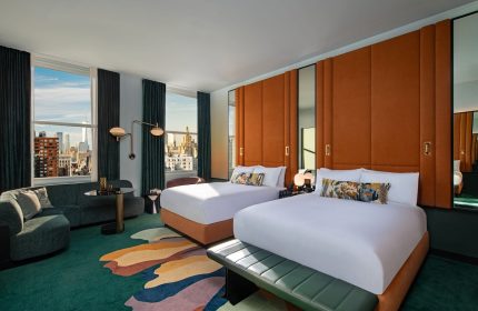 W New York - Union Square hotel room with two beds, city view, sofa, and colorful rug. A gay-friendly hotel for your travel plans.