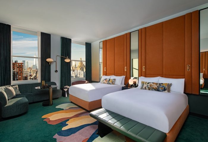 W New York - Union Square hotel room with two beds, city view, sofa, and colorful rug. A gay-friendly hotel for your travel plans.