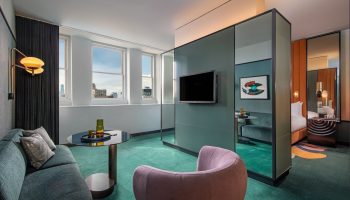 W New York - Union Square hotel room. Gay-friendly hotel interior with a seating area, TV, and view of the bedroom. Modern design.