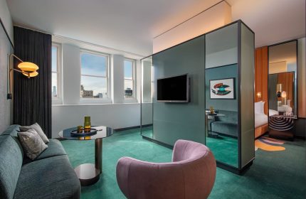 W New York - Union Square hotel room. Gay-friendly hotel interior with a seating area, TV, and view of the bedroom. Modern design.