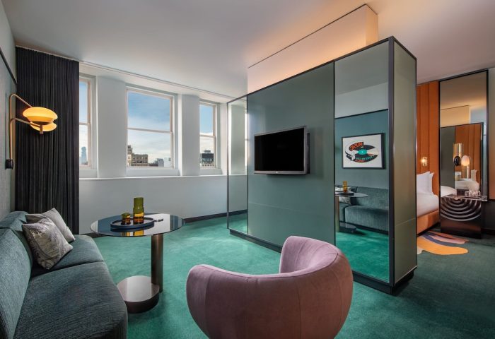W New York - Union Square hotel room. Gay-friendly hotel interior with a seating area, TV, and view of the bedroom. Modern design.