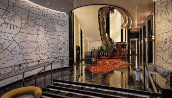 W New York - Union Square gay-friendly hotel lobby. Stylish design with unique wall art, staircase, and vibrant carpet. Upscale travel.