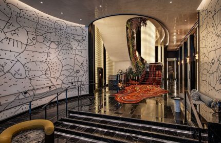 W New York - Union Square gay-friendly hotel lobby. Stylish design with unique wall art, staircase, and vibrant carpet. Upscale travel.