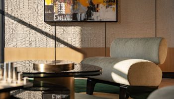 W New York - Union Square hotel interior. Modern chair, glass table, and art. Gay-friendly hotel design with textured wall and natural light.
