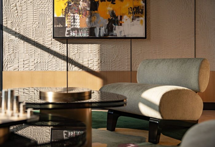 W New York - Union Square hotel interior. Modern chair, glass table, and art. Gay-friendly hotel design with textured wall and natural light.