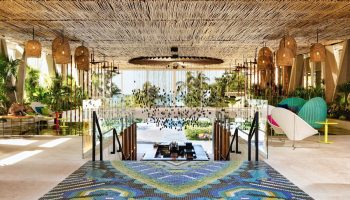 W Punta de Mita, a gay-friendly hotel. Lobby with colorful mosaic floor, straw ceiling, hanging lights, and ocean view. Chic design.