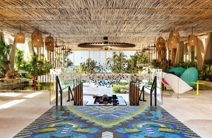W Punta de Mita, a gay-friendly hotel. Lobby with colorful mosaic floor, straw ceiling, hanging lights, and ocean view. Chic design.