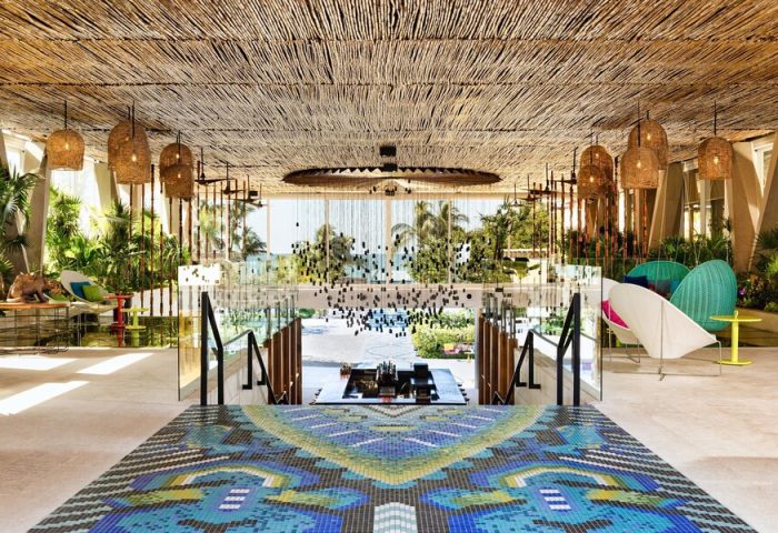 W Punta de Mita, a gay-friendly hotel. Lobby with colorful mosaic floor, straw ceiling, hanging lights, and ocean view. Chic design.
