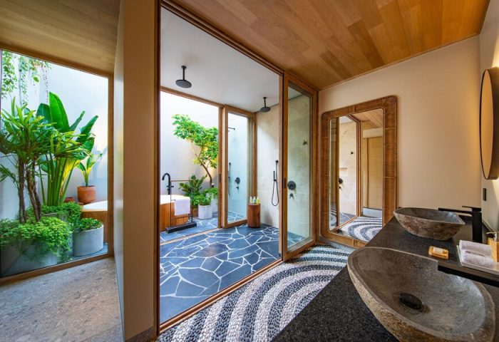 W Punta de Mita's luxury bathroom. Stylish sinks, mirror, & an outdoor shower/tub area with lush greenery. Gay-friendly hotel design.