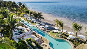 W Punta de Mita gay-friendly hotel: aerial view of pool, beach, and ocean. Palm trees and lounge chairs create a relaxing vibe for gay travelers.