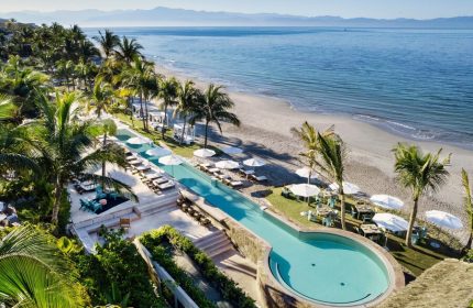 W Punta de Mita gay-friendly hotel: aerial view of pool, beach, and ocean. Palm trees and lounge chairs create a relaxing vibe for gay travelers.