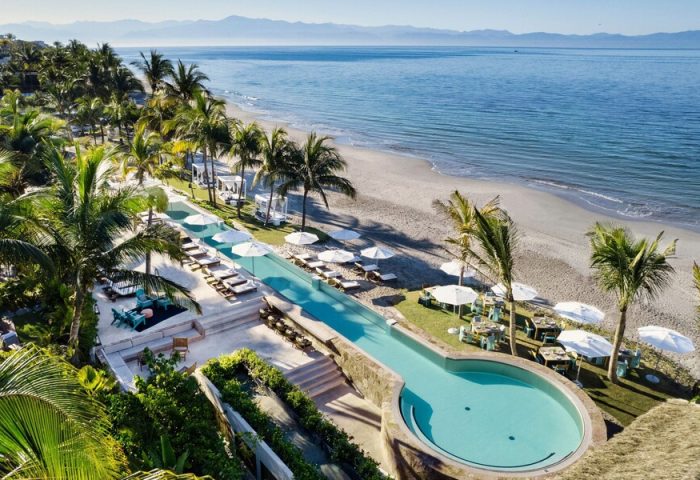 W Punta de Mita gay-friendly hotel: aerial view of pool, beach, and ocean. Palm trees and lounge chairs create a relaxing vibe for gay travelers.