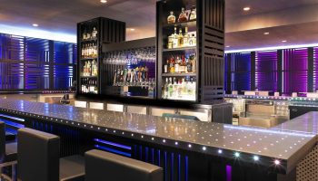 Bar at W San Francisco, a gay-friendly hotel. Modern design with liquor shelves, glasses, and beer taps. Blue and purple lighting.
