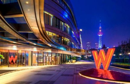 W Shanghai - The Bund at night. Gay-friendly hotel exterior view with the Oriental Pearl Tower in the background. Shanghai travel for gay men.