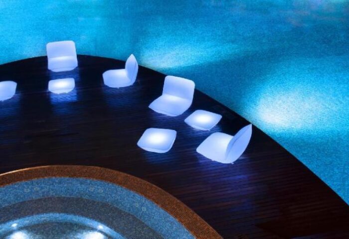 W Singapore Sentosa Cove gay-friendly hotel seating area. Illuminated chairs and tables near a blue pool. SG Clean Certified.