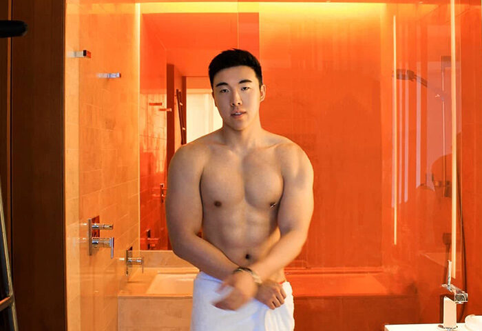 Gay-friendly W Taipei hotel: Asian man with muscular body in bathroom with orange decor. Gay travel advice, Taiwan hotel.