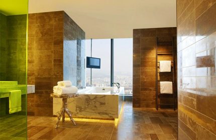 W Taipei gay-friendly hotel bathroom. Bathtub with city view. Towels on table, ladder rack. Modern design, luxury amenities.