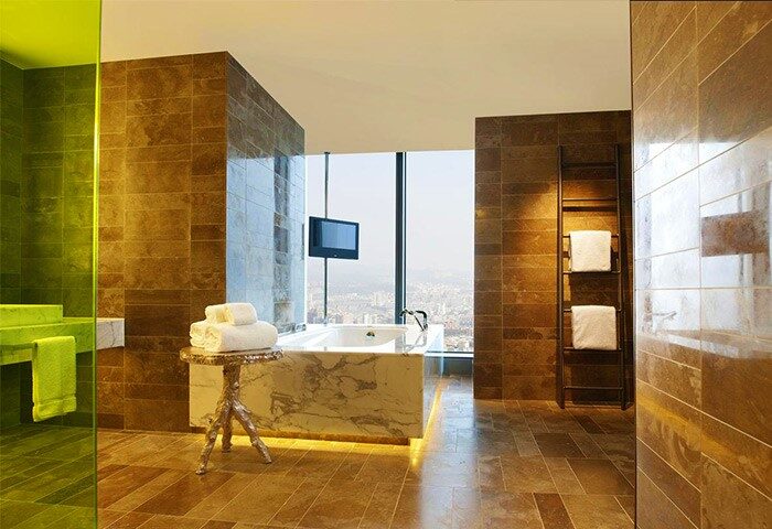 W Taipei gay-friendly hotel bathroom. Bathtub with city view. Towels on table, ladder rack. Modern design, luxury amenities.