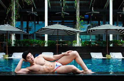 Gay-friendly W Taipei hotel: Muscular Asian man in swimwear lounges by the pool. Upscale travel for gay men in Taiwan.