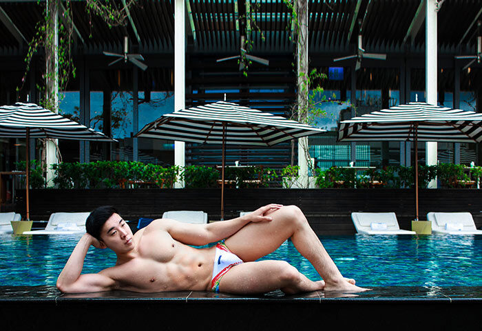 Gay-friendly W Taipei hotel: Muscular Asian man in swimwear lounges by the pool. Upscale travel for gay men in Taiwan.