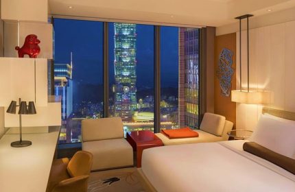 W Taipei gay-friendly hotel room at night. City view featuring Taipei 101. Modern design, luxury bedding, and stylish decor. Gay travel.