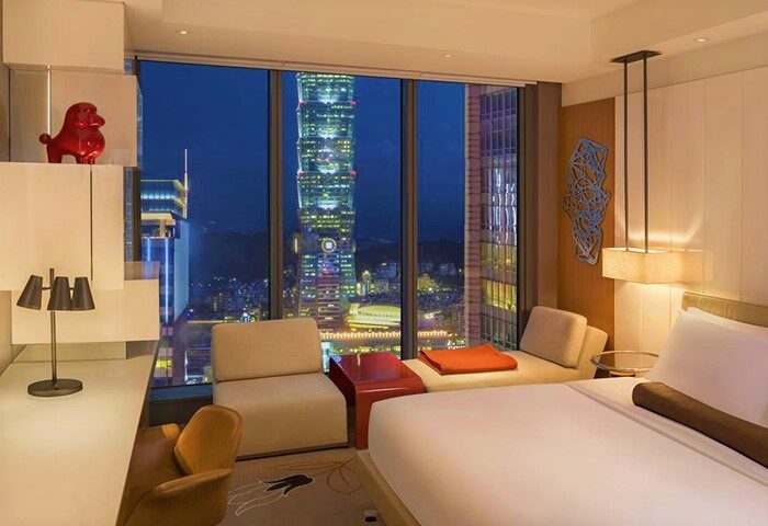 W Taipei gay-friendly hotel room at night. City view featuring Taipei 101. Modern design, luxury bedding, and stylish decor. Gay travel.