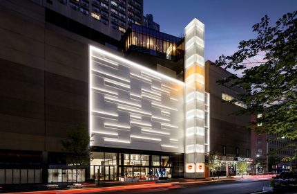 W Toronto, a gay-friendly hotel. The exterior features modern architecture with illuminated panels and a glass tower. Street view at night.
