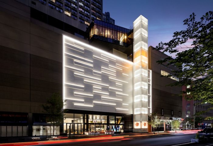 W Toronto, a gay-friendly hotel. The exterior features modern architecture with illuminated panels and a glass tower. Street view at night.