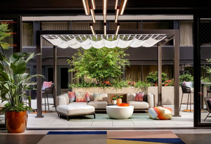 W Toronto gay-friendly hotel patio. Outdoor seating area with pergola, plants, and modern furniture. Stylish Toronto travel destination.