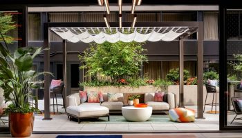 W Toronto gay-friendly hotel patio. Outdoor seating area with pergola, plants, and modern furniture. Stylish Toronto travel destination.