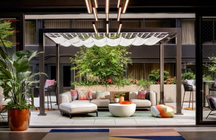 W Toronto gay-friendly hotel patio. Outdoor seating area with pergola, plants, and modern furniture. Stylish Toronto travel destination.