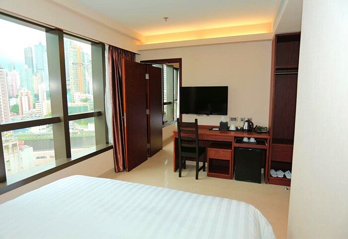 WE Hotel's gay-friendly room with city view. Modern interior with desk, TV, and large window. Ideal for gay travel and comfortable stays.