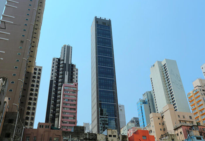 WE Hotel: Low-angle view of the Gay-Friendly-Hotel-WE-Hotel, showcasing its modern architecture amidst other buildings against a clear sky.