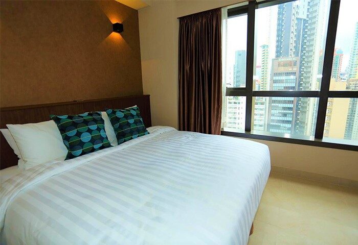 WE Hotel room interior. Gay-friendly hotel with bed, pillows, and city view. Modern design. Comfortable stay for gay travelers.